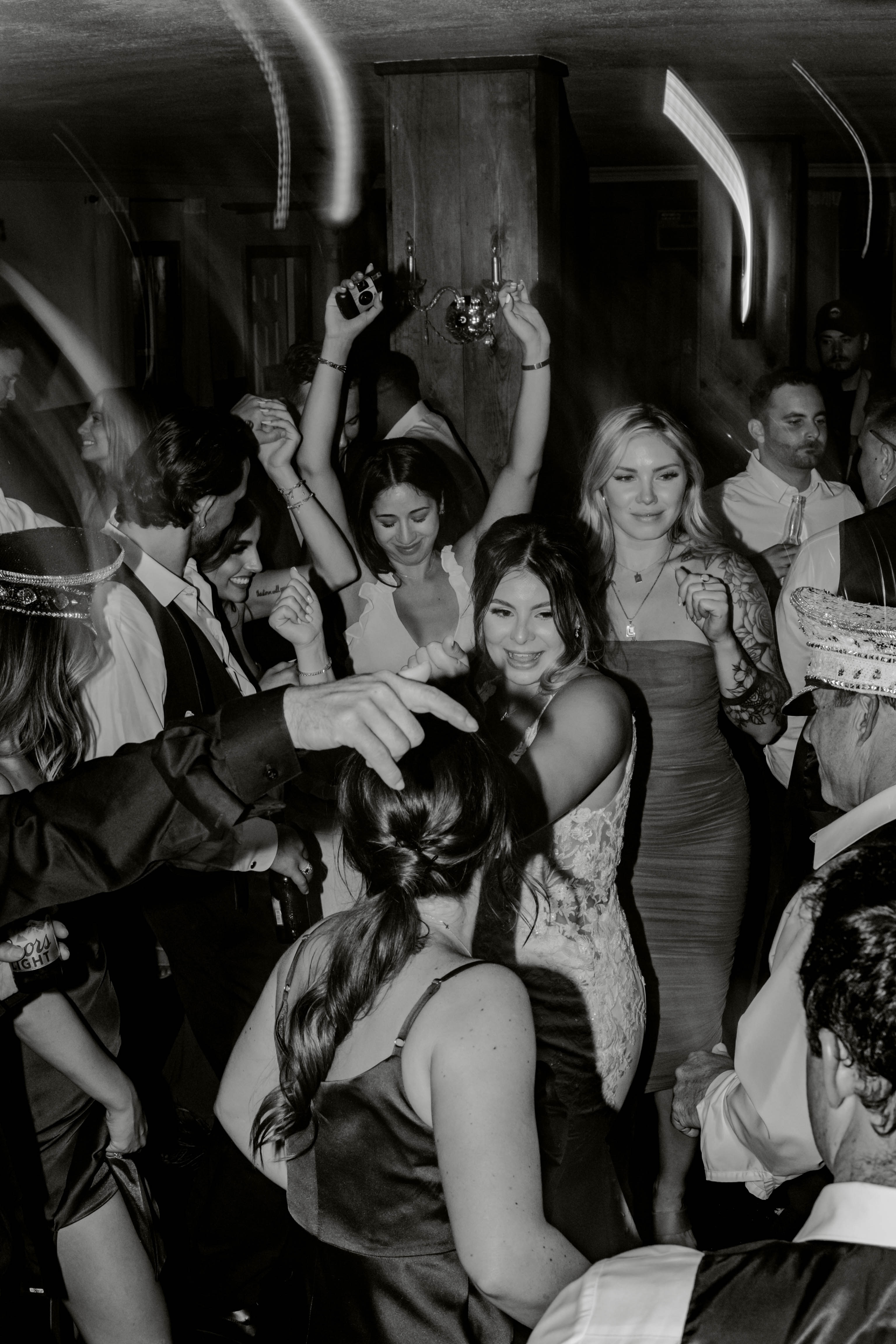 A laughing bride dances in a crowd of guests waving light sticks